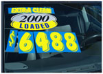 A used car window displaying a dealership sale sign