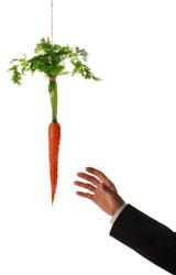 A carrot dangling on a string in front of a man's hand