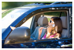 A woman driving while talking on her cell phone and applying lipgloss