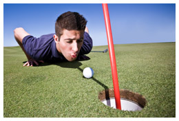 Golfer blowing his ball into the hole