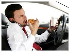 Man eating, drinking coffee, talking on a cell phone and driving