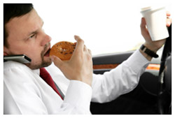 A man eating, drinking coffee, taking on the phone and driving